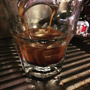 Thick Valmandin crema flowing from the portafilter spout into a glass cup.