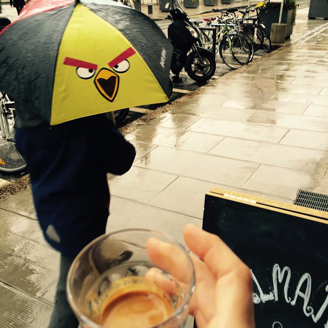 A delicious cup of Valmandin espresso in a glass cup being offered to an Angry Bird on an umbrella.